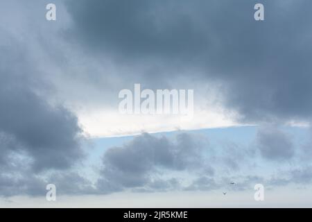 Blue sky with white cloud streak, and big gray clouds in front Stock Photo