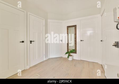 Interior of modern flat in minimal style with narrow empty corridor illuminated by lamps Stock Photo