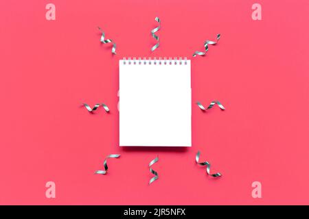 Blank notepad mockup with ribbons confetti on a pink background. Stock Photo