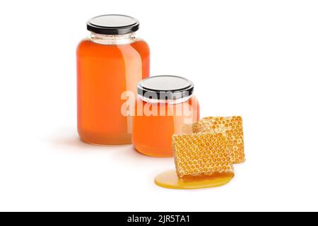 Two jars of honey and pieces of honeycomb isolated on white background Stock Photo