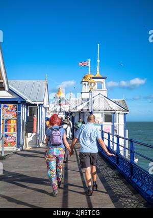 A couple walks hand-in-hand down Eastbourne Pier, East Sussex, UK. Stock Photo