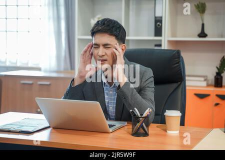 Tired depressed bored and Panicked businessman Stressed working in contemporary office looking at laptop feel problem at work casual attire workplace Stock Photo