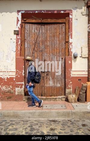 young man walking with a cane, wearing a rancher's hat, in the background an old wooden door Stock Photo
