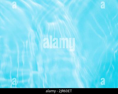 Ripple water texture on blue pool background. Shadow of water on sunlight. Mockup for product, spa or travel background. Marble blue water surface as wallpaper background Stock Photo