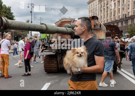 Kyiv, Ukraine. 20th Aug, 2022. A man with a dog in his arms is visible against the background of the destroyed self-propelled guns. An exhibition of destroyed Russian equipment is being organized on Khreshchatyk. Six months ago, this military equipment were ordered by the Russian president Vladimir Putin to invade Ukraine. He reportedly reckoned that they would capture Kyiv in three days. Credit: SOPA Images Limited/Alamy Live News Stock Photo