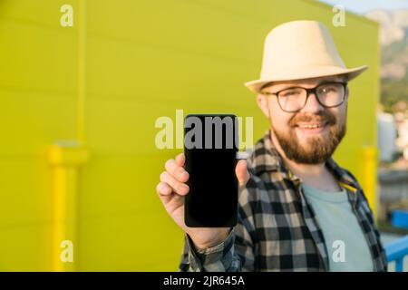 Hot offering. Happy guy holds cellphone with black copy space and smiling. Human emotions facial and place for advertising and text Stock Photo