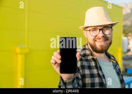 Hot offering. Happy guy holds cellphone with black copy space and smiling. Human emotions facial and place for advertising and text Stock Photo