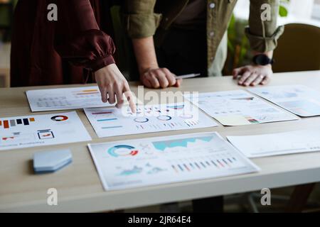 Close-up of couple of colleagues pointing at documents and discussing them in team at table Stock Photo