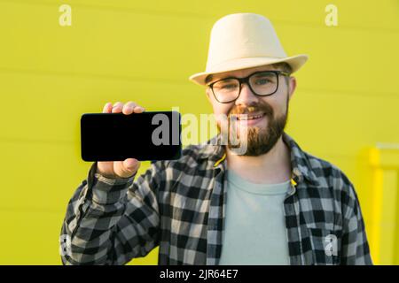 Hot offering. Happy guy holds cellphone with black copy space and smiling. Human emotions facial and place for advertising and text Stock Photo