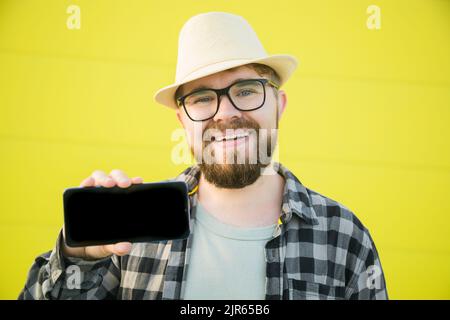 Hot offering. Happy guy holds cellphone with black copy space and smiling. Human emotions facial and place for advertising and text Stock Photo
