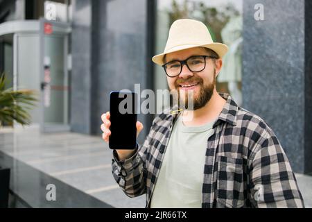 Hot offering. Happy guy holds cellphone with black copy space and smiling. Human emotions facial and place for advertising and text Stock Photo
