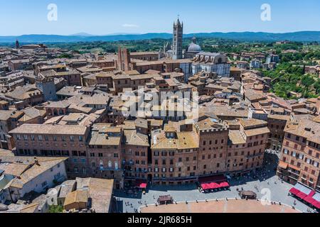 View from top of Torr del Mangia bell tower looking down on Piazza del Campo and the red tiled rooftops beyond to the Duomo in Siena, Tuscany, Italy Stock Photo