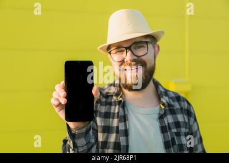 Hot offering. Happy guy holds cellphone with black copy space and smiling. Human emotions facial and place for advertising and text Stock Photo
