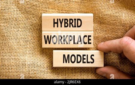 Hybrid workplace models symbol. Concept words Hybrid workplace models on wooden blocks. Businessman hand. Beautiful canvas background. Business hybrid Stock Photo