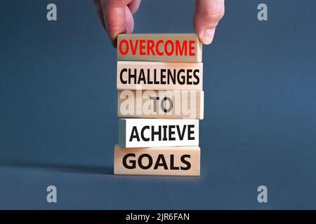 Overcome challenges to achieve goals symbol. Concept words Overcome challenges to achieve goals on wooden blocks on a beautiful grey background. Busin Stock Photo