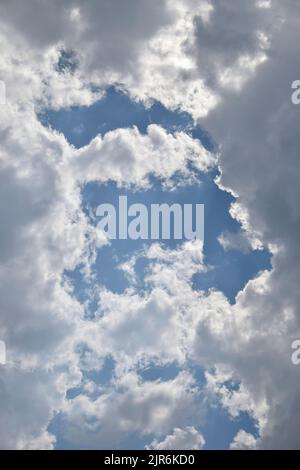 Beautiful cloudy sky. Frame made of clouds. Blue sky with lots of white fluffy cumulus clouds, natural background, full frame. Selective focus. Stock Photo