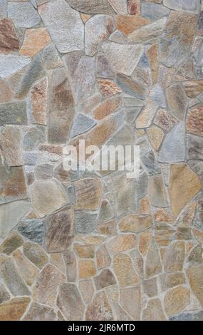 Front view of stone wall made of weathered and multi-colored stone slates. Abstract high resolution full frame textured background. Stock Photo