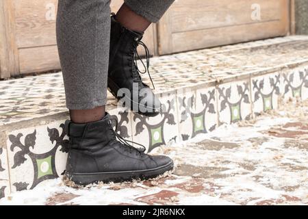 women's legs in boots in the winter on the street in the city, women's boots on the snow Stock Photo