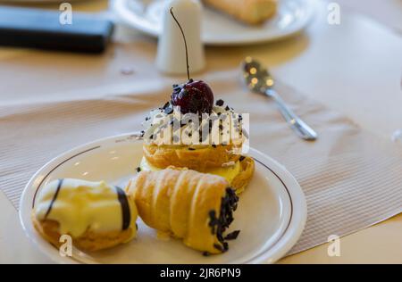 Close up view of three small cakes with cherry berry on white plate. Stock Photo