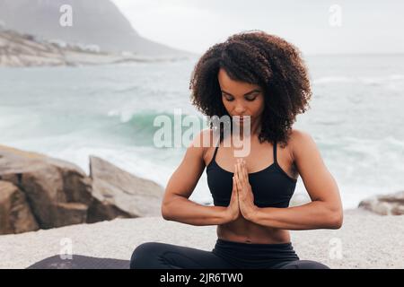 Woman with closed eyes sitting in prayer pose. Female practicing yoga with folded hands. Stock Photo