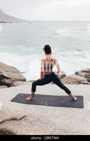 Rear view of young woman practicing yoga tree pose on beach, Dominican ...