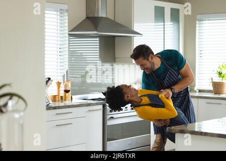Image of happy diverse couple dancing in kitchen Stock Photo
