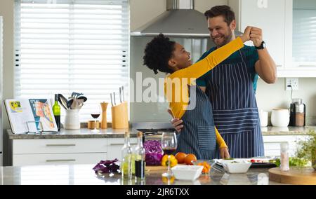 Image of happy diverse couple dancing in kitchen Stock Photo