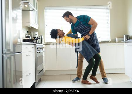 Image of happy diverse couple dancing in kitchen Stock Photo