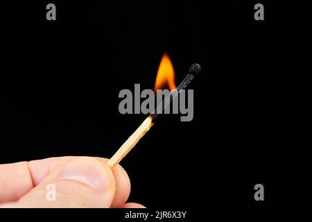 A man holds a burning match in his hand on a dark background Stock Photo