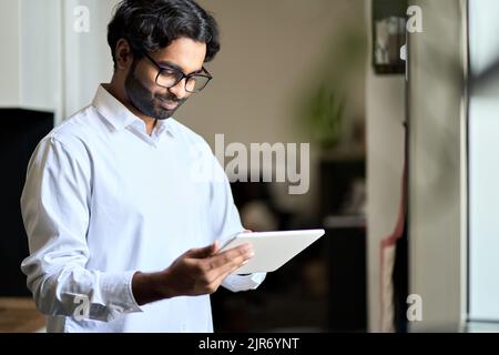 Smiling young indian business man employee using digital tablet. Stock Photo