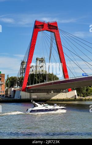 Rotterdam, Netherlands - August 2022: Luxury motor boat about to pass under the Willems Bridge, which is a cable stayed bridge in the city centre Stock Photo