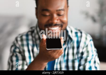 Happy Black Man Using Voice Assistant Application On Phone Indoors Stock Photo