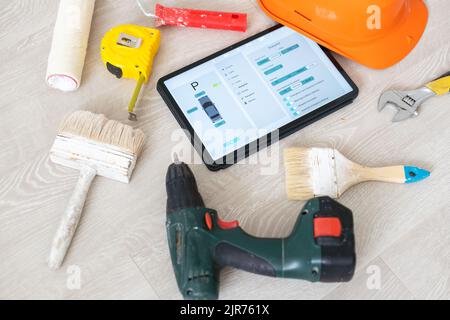 Different equipment tools of builder and tablet pc on wooden texture. Stock Photo