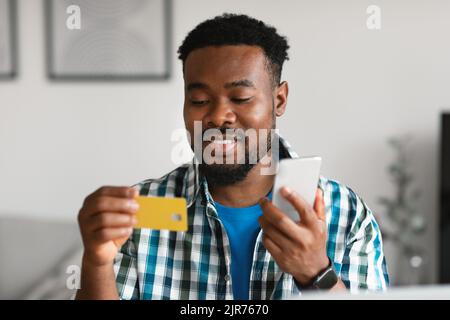 African American Man Using Credit Card And Smartphone At Home Stock Photo