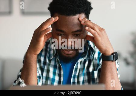 Thoughtful Black Guy Using Laptop Having Business Problems At Workplace Stock Photo