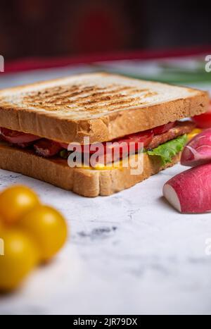 sandwich of two bread toasts close-up with stuffing and vegetables on a wooden board top view Stock Photo