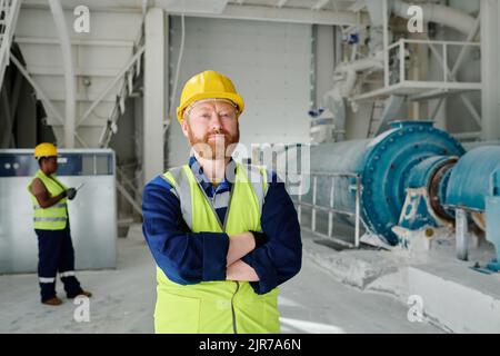 Successful middle aged engineer or worker of marble plant in uniform looking at camera while keeping his arms crossed on chest Stock Photo