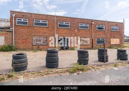 Car tyres stacked in front of abandoned building in an industrial estate, port area of Great Yarmouth, Norfolk, England. Stock Photo