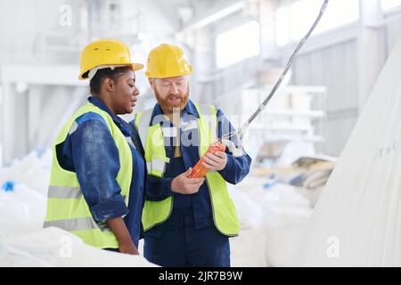 Confident male engineer consulting AFrican American female colleague about how to use switch remote control in workshop Stock Photo