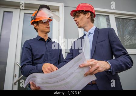 Two colleagues discuss using a floor plan, engineers at work Stock Photo