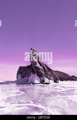 Frozen Baikal lake with transparent cracked blue ice and Ogoy island. Toned in trendy color. Siberia, Russia. Beautiful winter landscape. Stock Photo