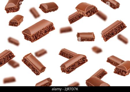 Falling porous chocolate pieces, isolated on white background, selective focus Stock Photo