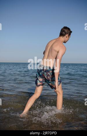A 17 Year Old Teenage Boy Walking Into The Sea Stock Photo