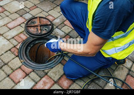 service worker cleaning blocked sewer line with hydro jetting Stock Photo