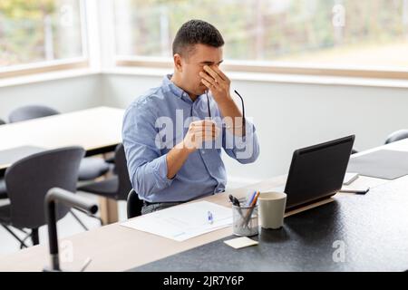 tired man with laptop working at home office Stock Photo