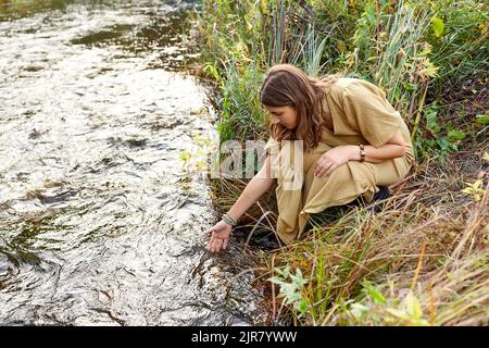 woman or witch performing magic ritual on river Stock Photo