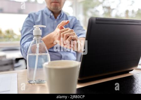 man using hand sanitizer at home office Stock Photo