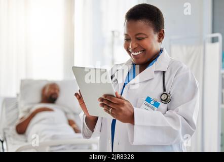 Happy news with doctor reading exciting email or test results on digital tablet, feeling positive at hospital. Young health care worker getting good Stock Photo