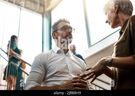 We should collaborate on the next project. two businesspeople talking to each other while standing on a stairwell. Stock Photo