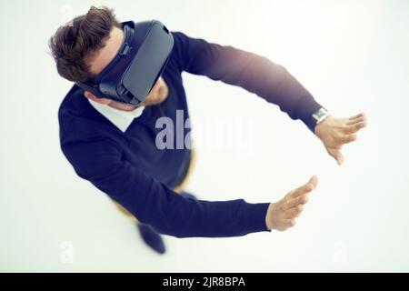 Change the way you see and experience the world. High angle shot of a businessman wearing a VR headset in an office. Stock Photo